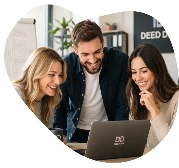 Three colleagues gathered around a laptop, smiling as they look at the screen in a bright office; the laptop shows a DD Deep Design logo.